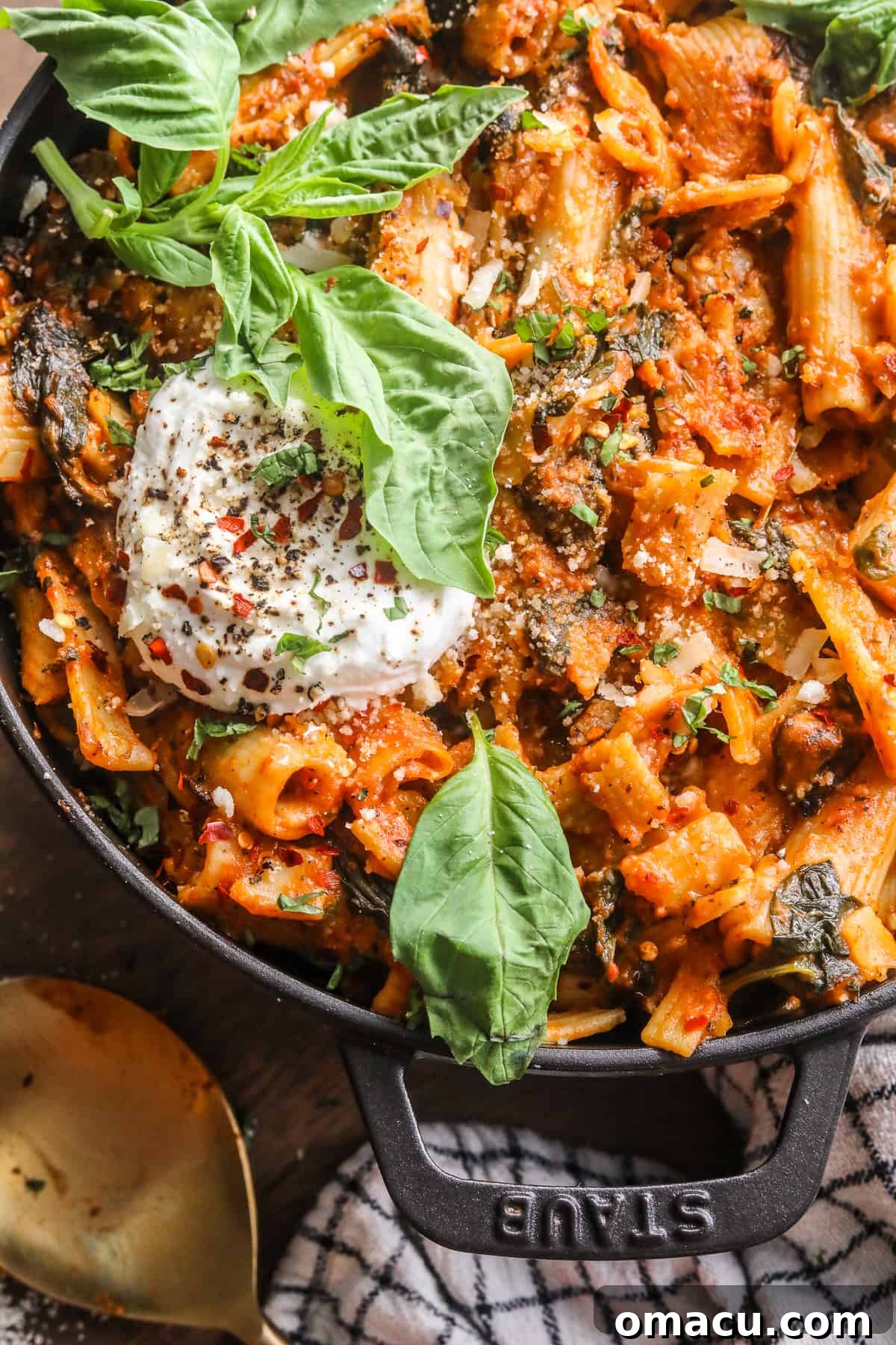 Close-up of creamy tomato pasta in a pot, generously topped with fresh basil and dollops of burrata cheese.
