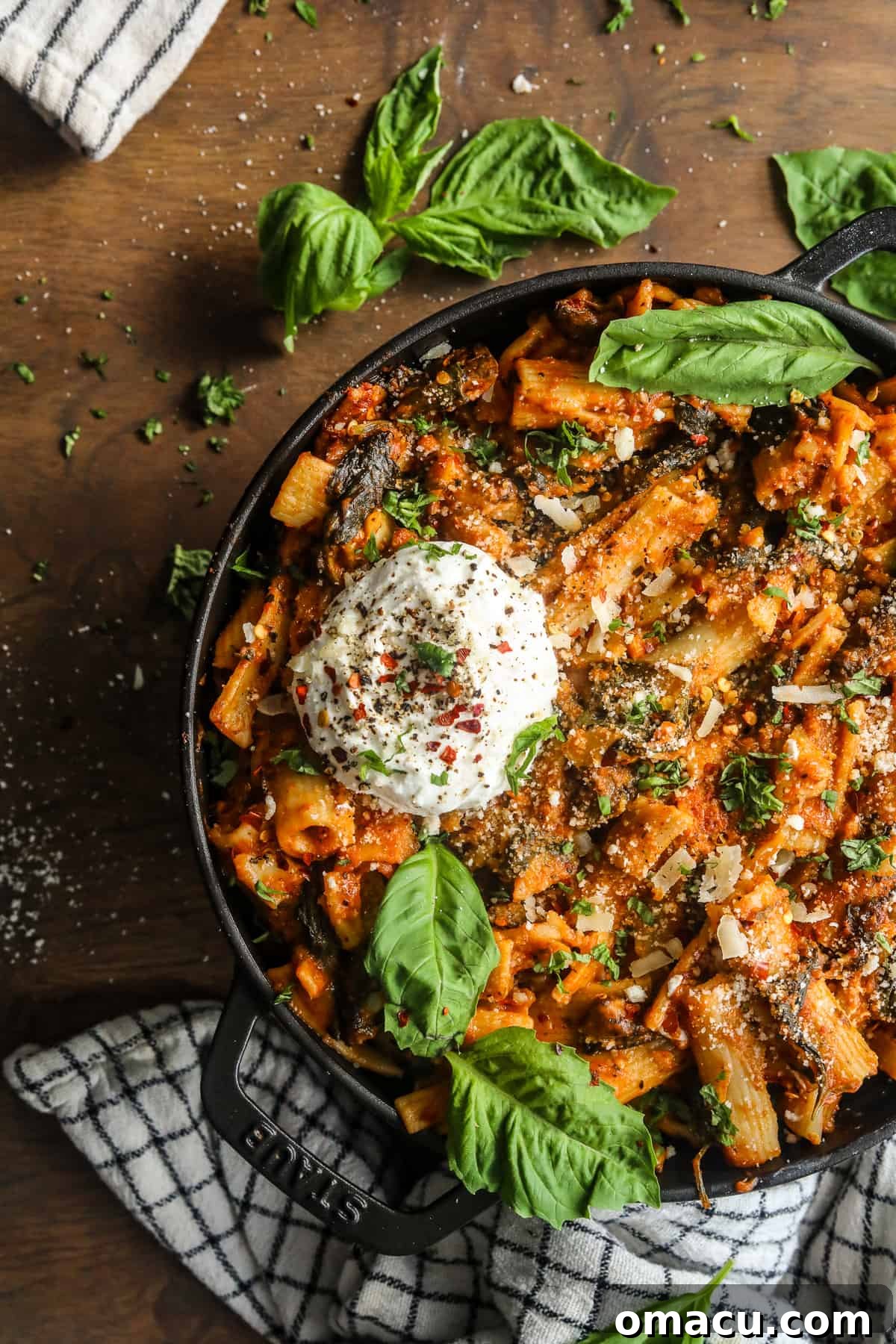 Overhead view of a bowl of creamy tomato pasta with fresh herbs and a drizzle of olive oil.