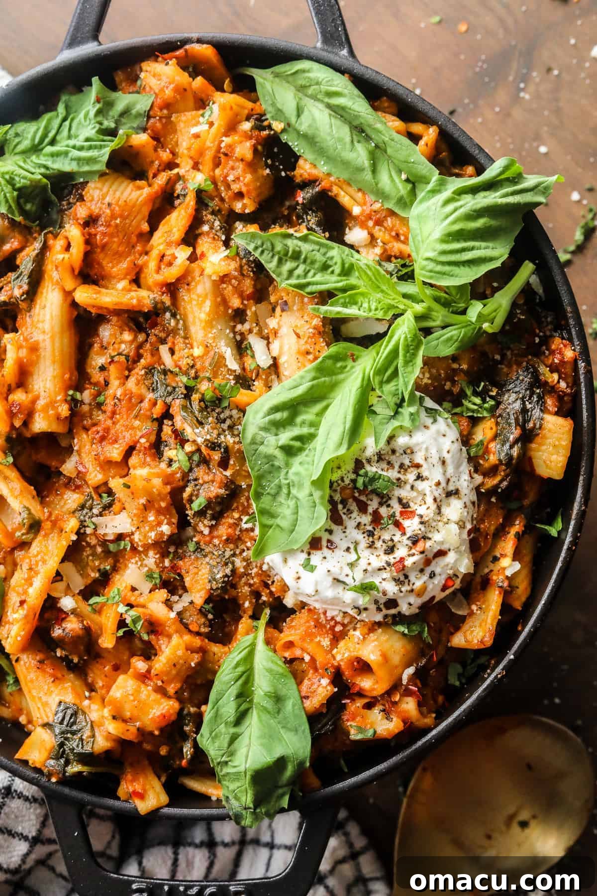 A large pot filled with creamy tomato pasta, garnished with fresh basil leaves, ready to be served.