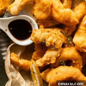 Beer battered shrimp on a plate with malt vinegar in a small bowl.