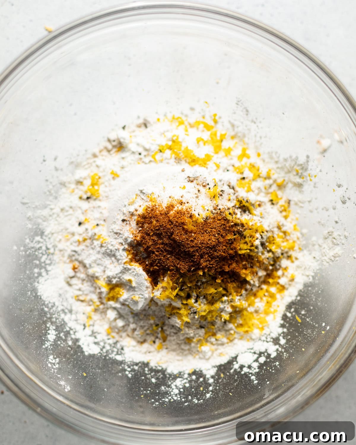 A bowl containing a dry mixture of flour, lemon zest, old bay seasoning, baking powder, and kosher salt, the base for the beer batter.