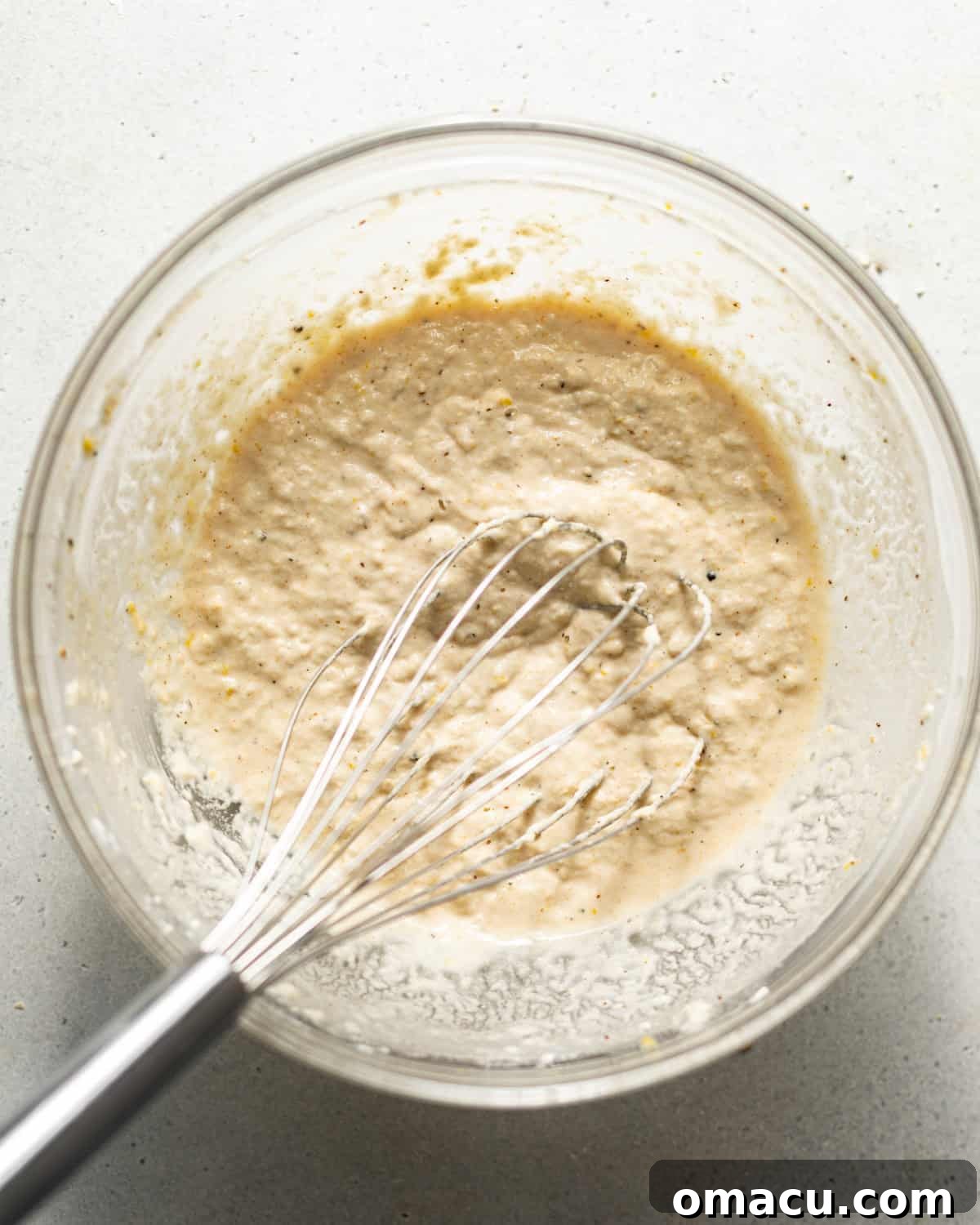 The beer batter mixture after cold beer and vodka have been added and whisked until just combined, showing a smooth consistency.