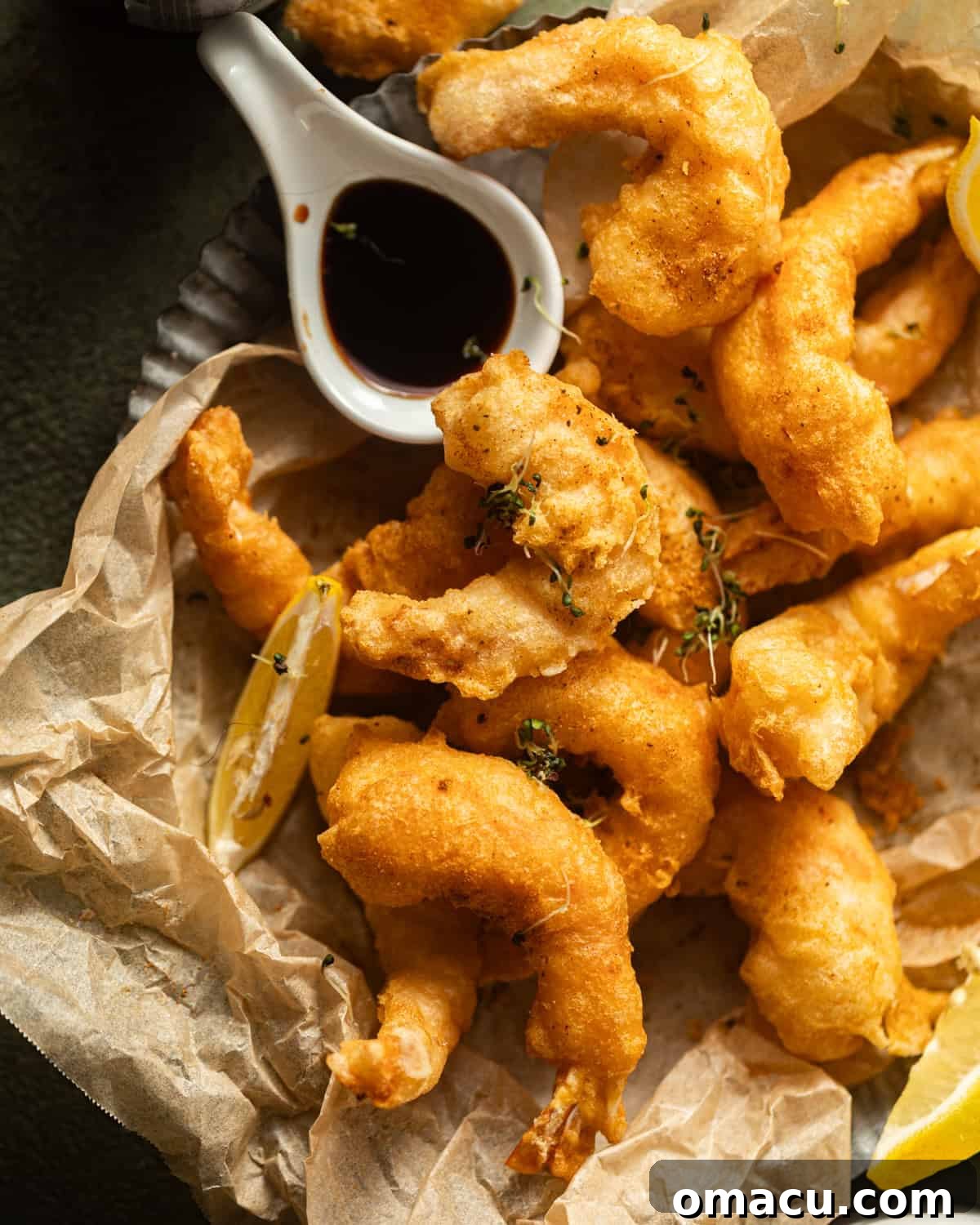 A silver platter lined with parchment paper, generously filled with golden fried shrimp, dusted with Old Bay seasoning.