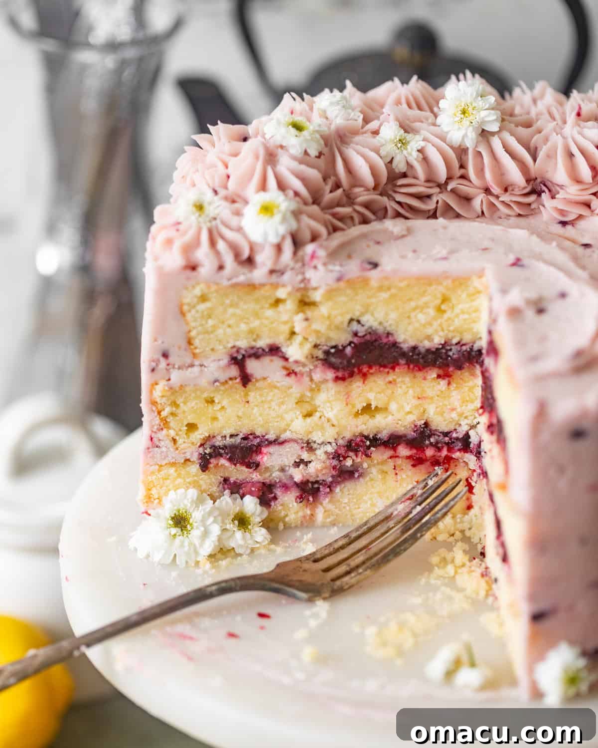 A beautifully sliced Lemon Blackberry Cake revealing its moist lemon layers and vibrant blackberry filling.