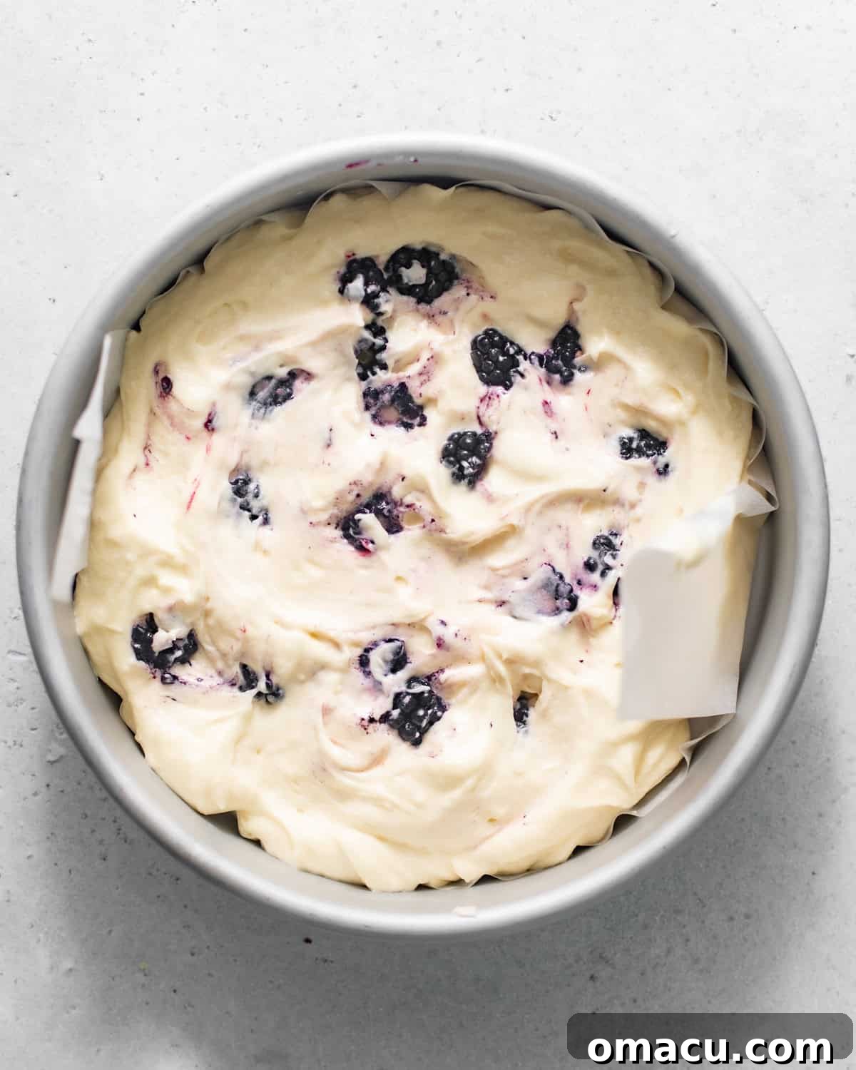 Cake batter evenly divided into a cake pan lined with parchment paper.