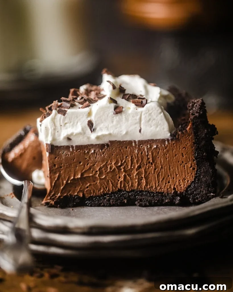 a slice of chocolate mousse pie on a plate topped with whipped cream and chocolate curls.