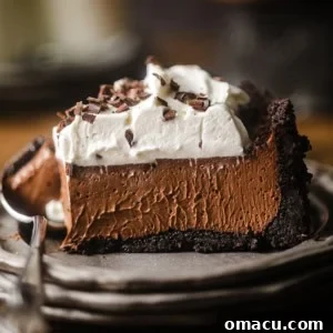 a slice of chocolate mousse pie on a plate topped with whipped cream and chocolate curls.