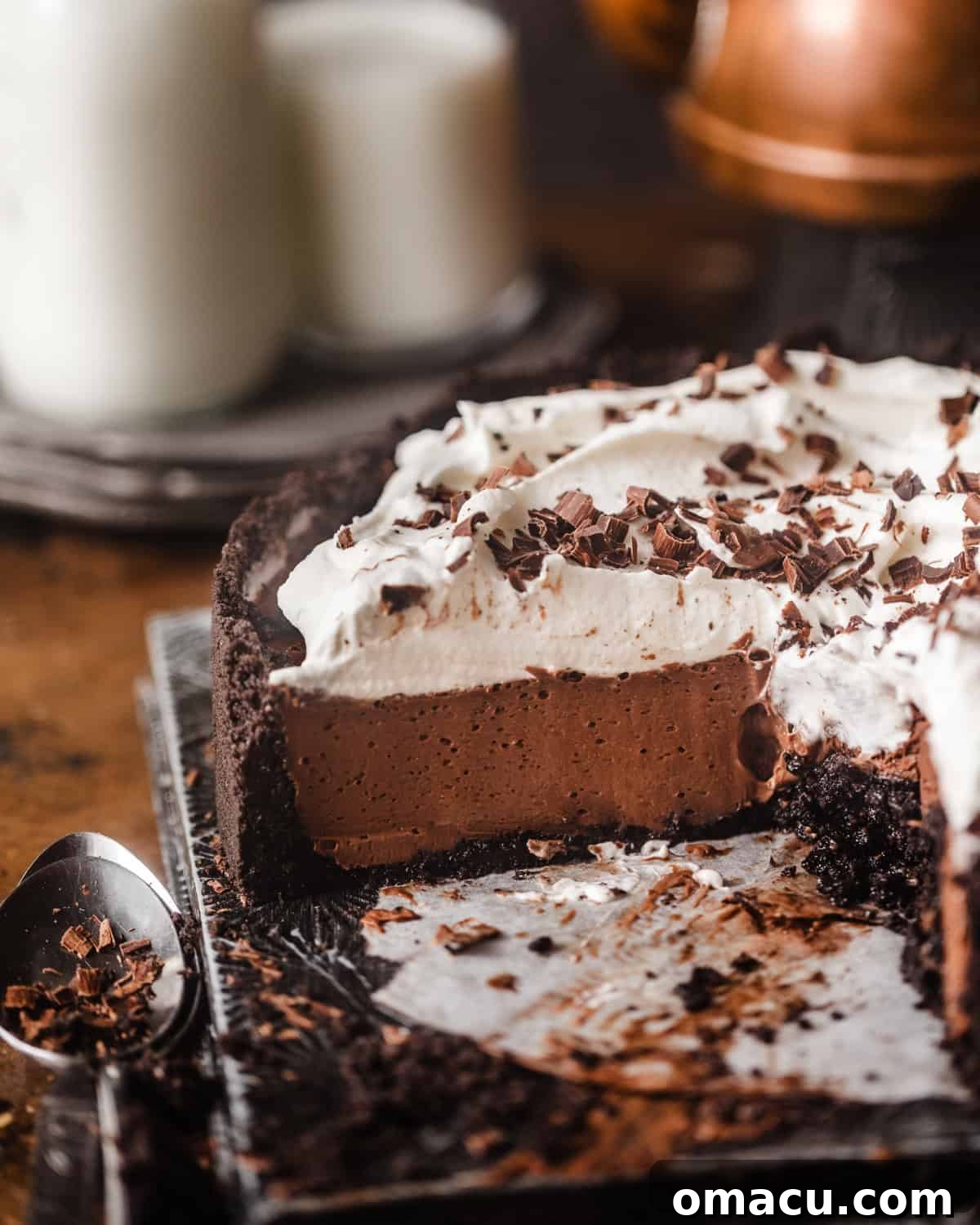 chocolate mousse pie on a serving plate topped with whipped cream and chocolate shavings. 