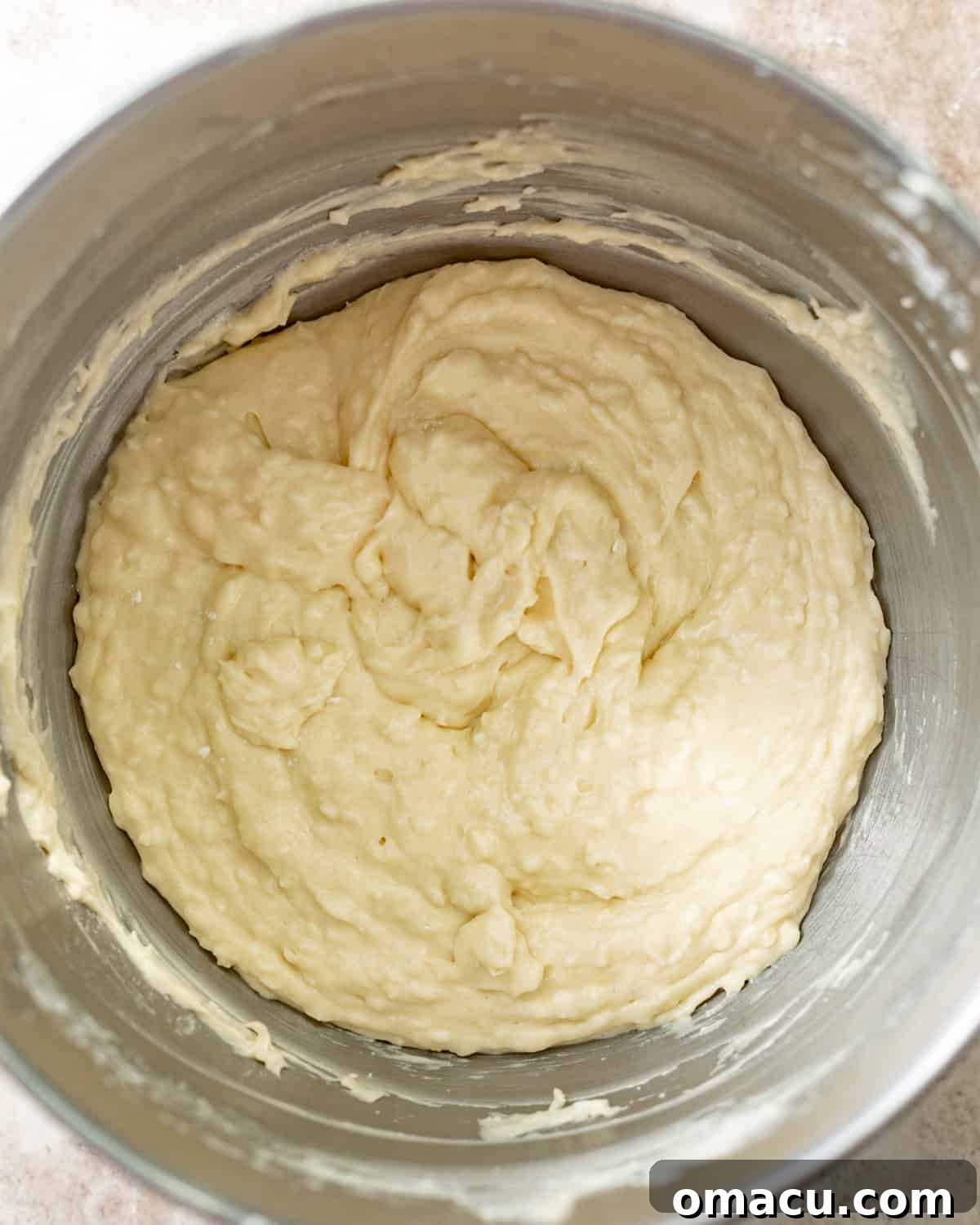 The perfectly smooth, creamy, and well-mixed coconut loaf cake batter residing in a large mixing bowl, its texture indicating readiness for baking and promising a moist, tender result.
