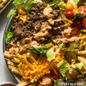 Big Mac Salad in a bowl topped with ground beef, tomatoes, cheddar cheese, pickles, and special sauce, presented beautifully for serving.