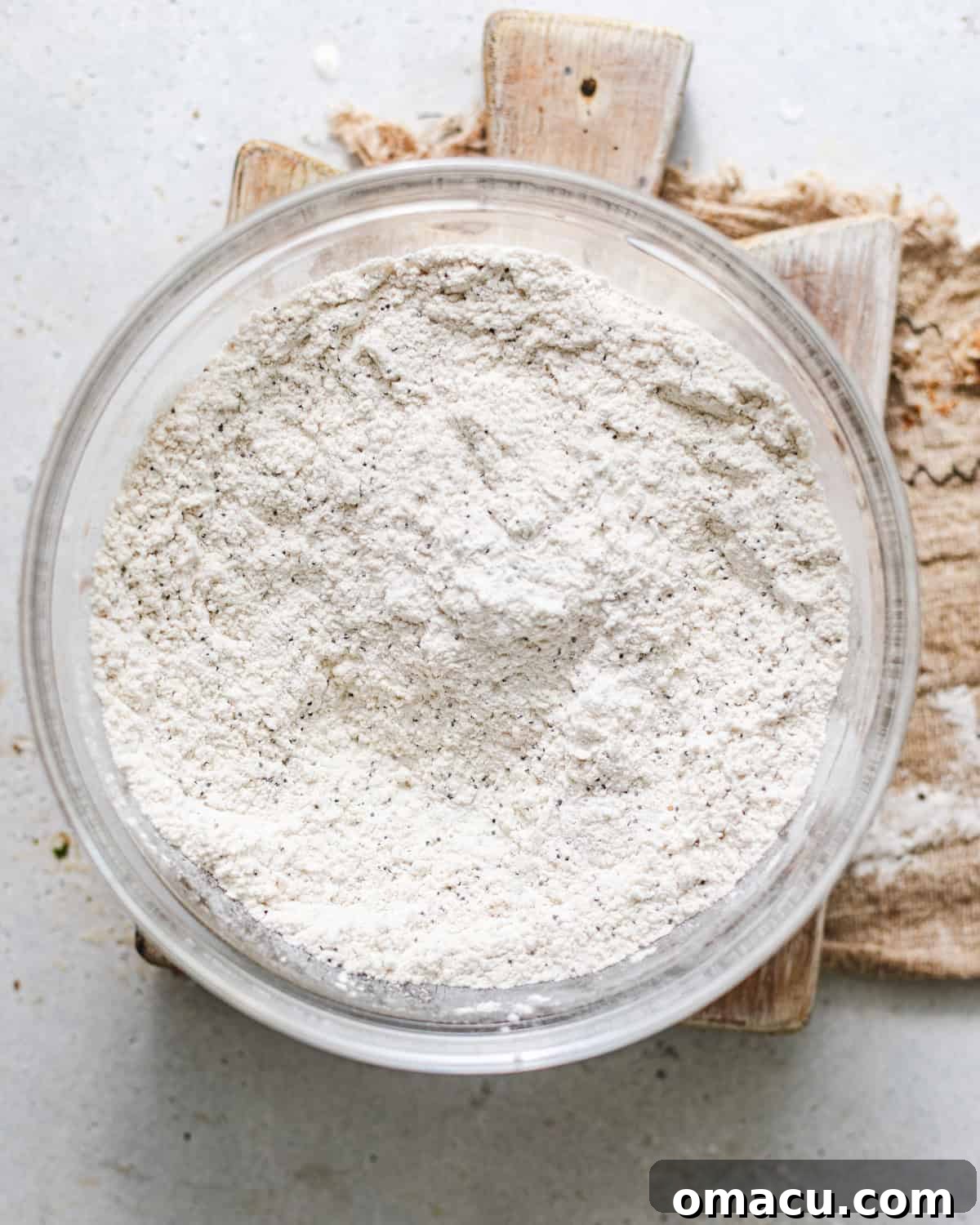 Dry ingredients like flour, baking powder, baking soda, and spices, whisked together in a separate bowl before adding blueberries.