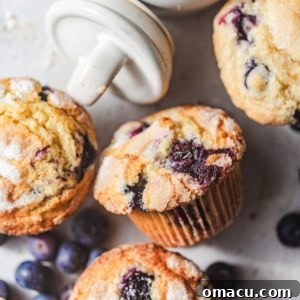 Close-up of a bakery-style blueberry muffin, showcasing its golden crumb and juicy blueberries, ready to be served.