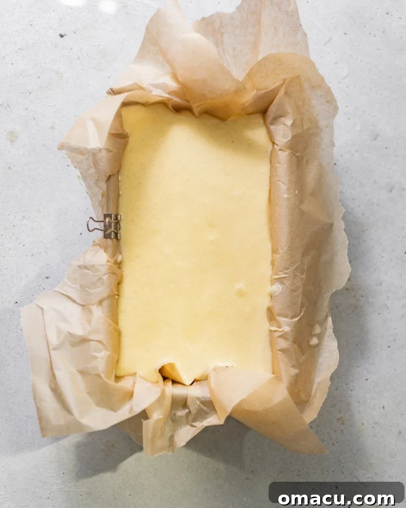 Creamy Basque cheesecake batter poured into a parchment-lined loaf pan, ready for its signature 'burnt' bake.
