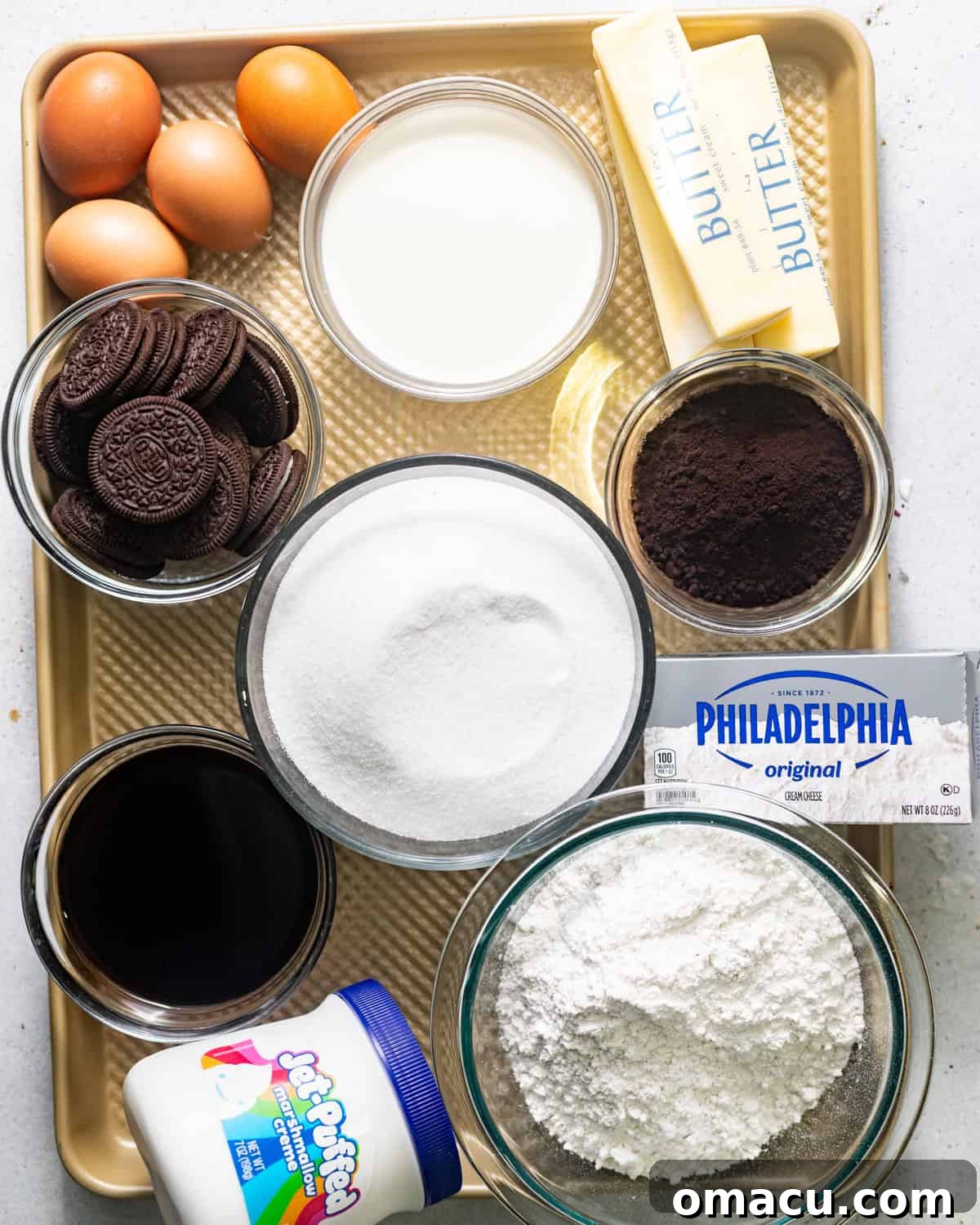 Essential ingredients laid out for making Oreo pound cake, including butter, shortening, oil, sugar, vanilla extract, heavy cream, cake flour, baking powder, kosher salt, cream cheese, black cocoa powder, and coffee.