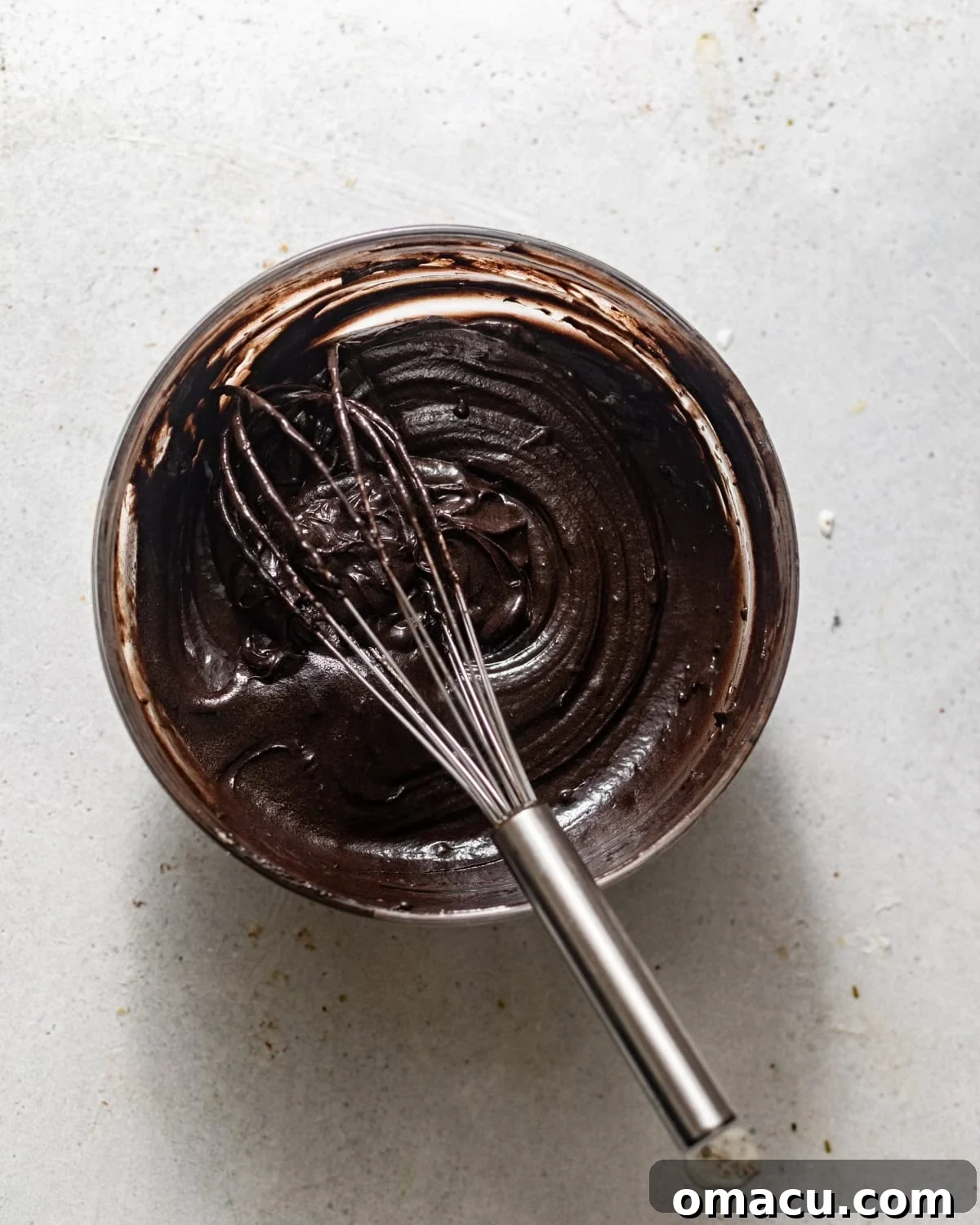 A portion of cake batter being mixed with black cocoa powder and hot coffee in a separate bowl to create the dark swirl component.