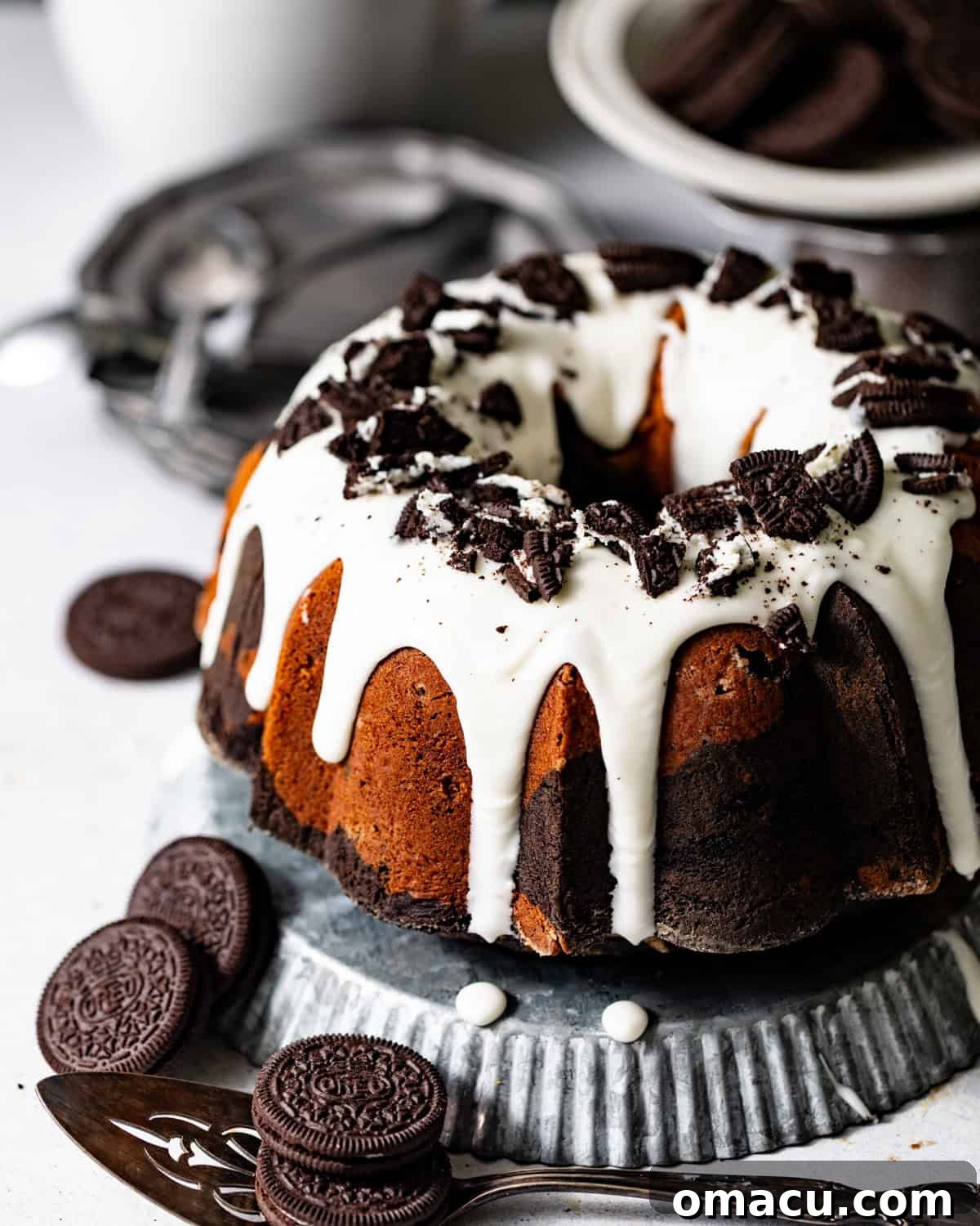 A stunning Oreo pound cake, beautifully glazed with cream cheese and topped with crushed Oreos, presented on a elegant serving tray.