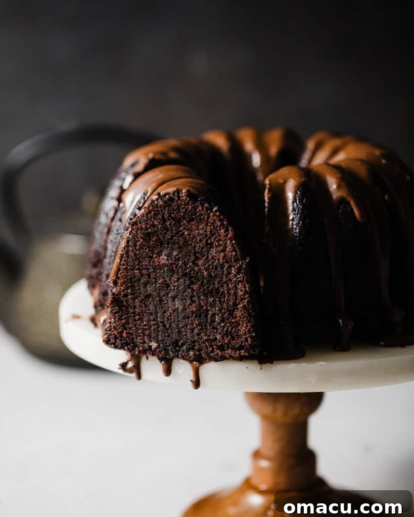 A slice of the magnificent chocolate donut cake, revealing its moist interior and rich chocolate glaze, served on a cake stand.