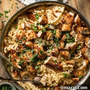Garlic Parmesan pasta with chicken in a large skillet with a kitchen towel on the pan, showcasing the delicious meal.