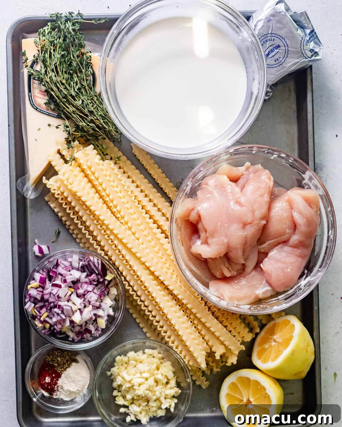 Ingredients laid out for garlic parmesan pasta with chicken: heavy cream, chicken, garlic, parsley, pasta, lemon, hot sauce, shallots, thyme, cream cheese, parmesan, seasonings, olive oil, and butter.