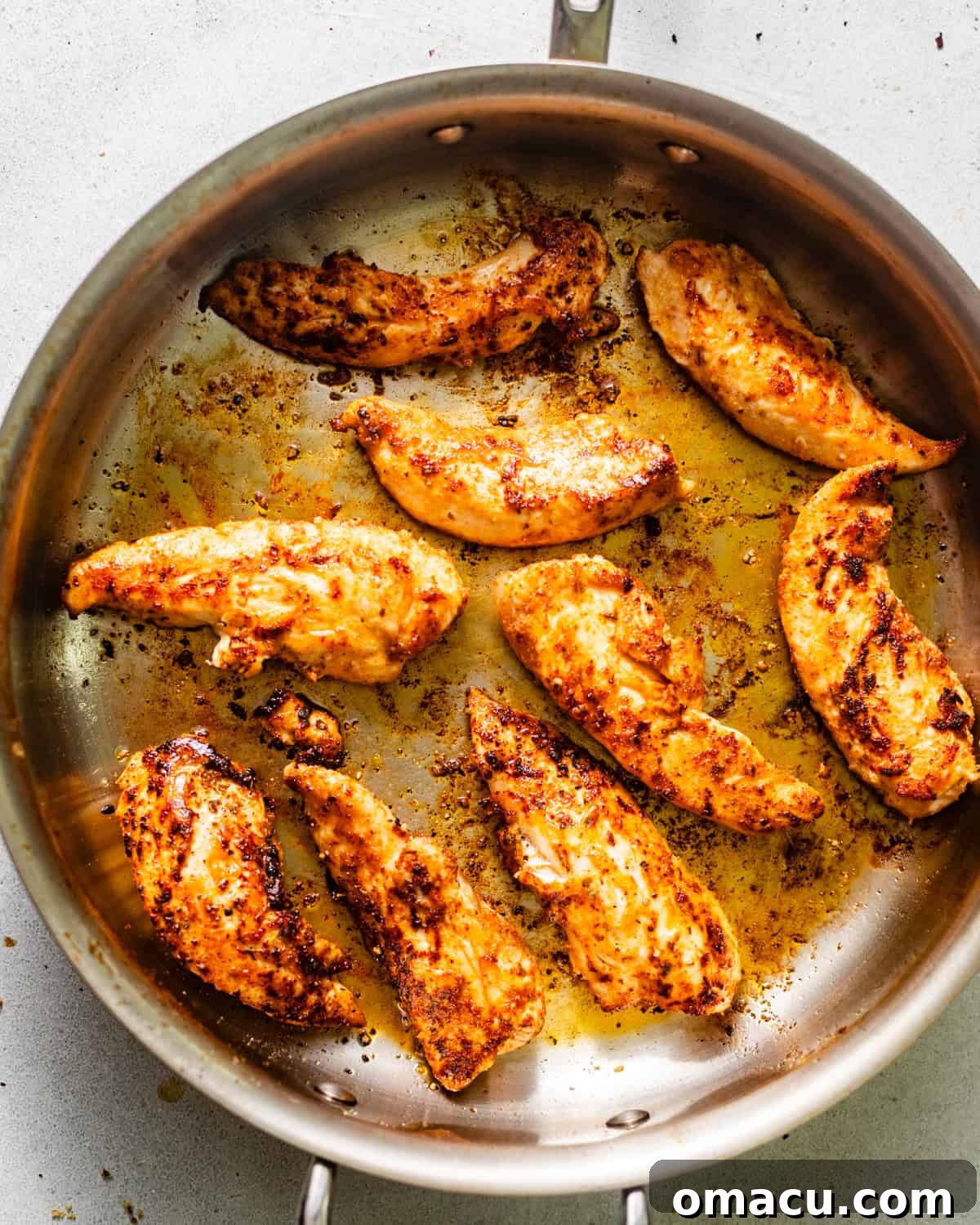 Chicken tenderloins coated in seasonings and seared to a golden-brown perfection in a skillet.