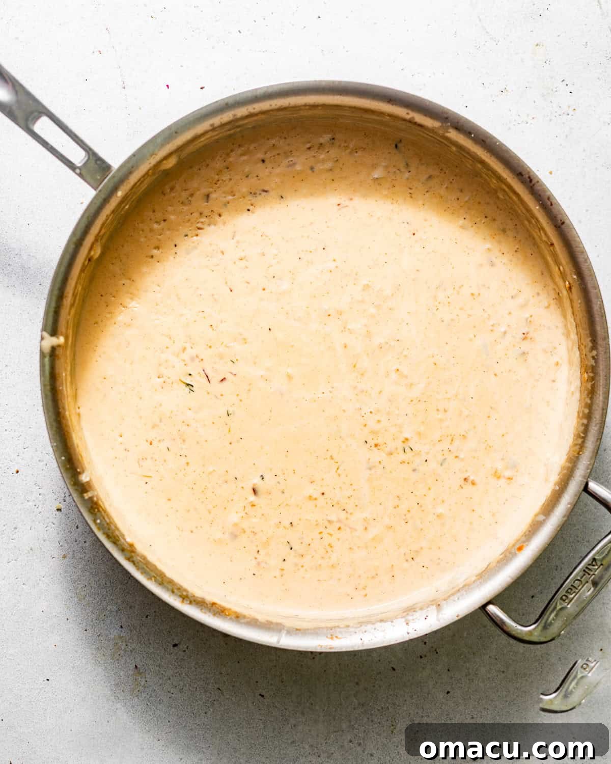 Rich and creamy garlic parmesan sauce simmering in a skillet, thickened to perfection.