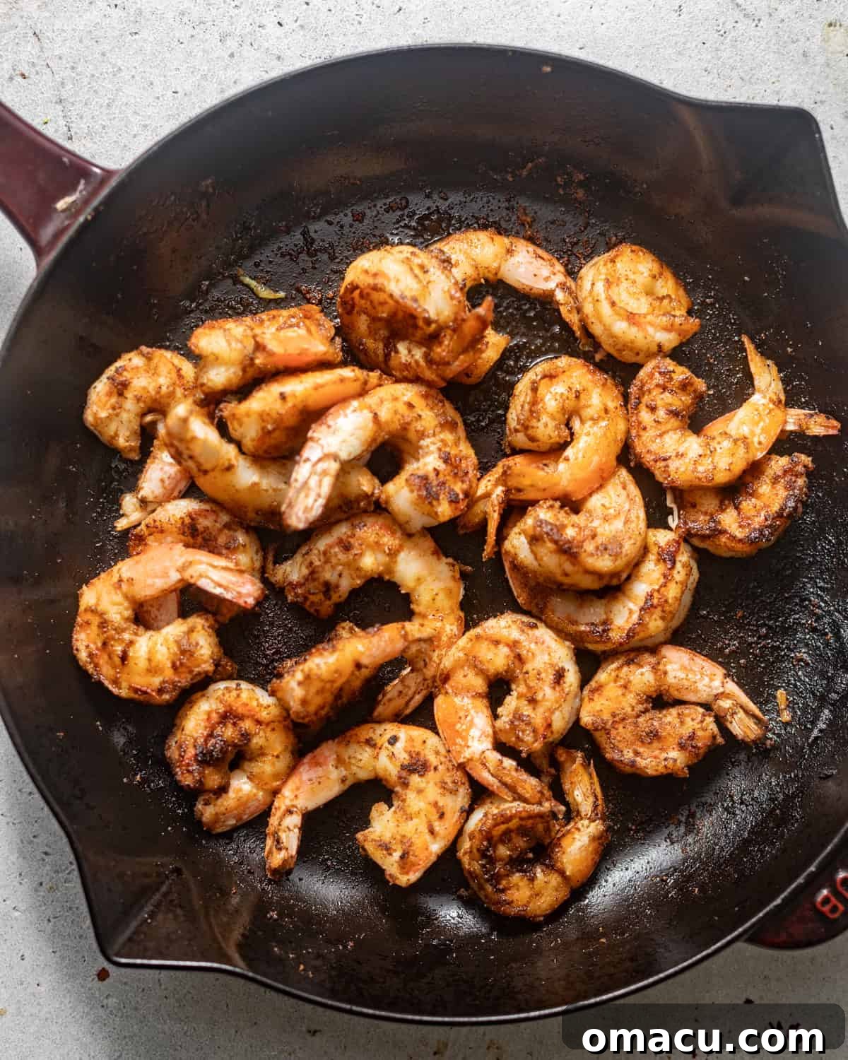 Pan-fried seasoned shrimp cooking in a hot skillet until perfectly pink and curled.