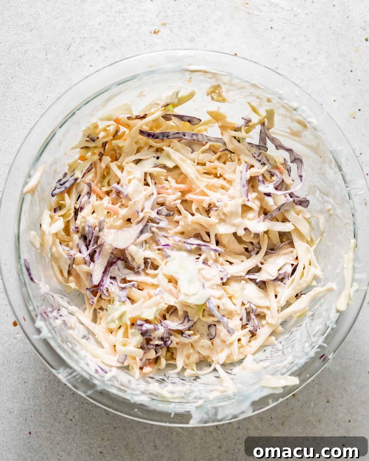 Coleslaw mix thoroughly combined with its creamy, tangy dressing in a large bowl.