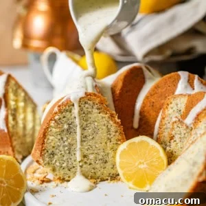 lemon poppy seed cake on a plate with a cup pouring lemon cream cheese glaze on top of the cake.