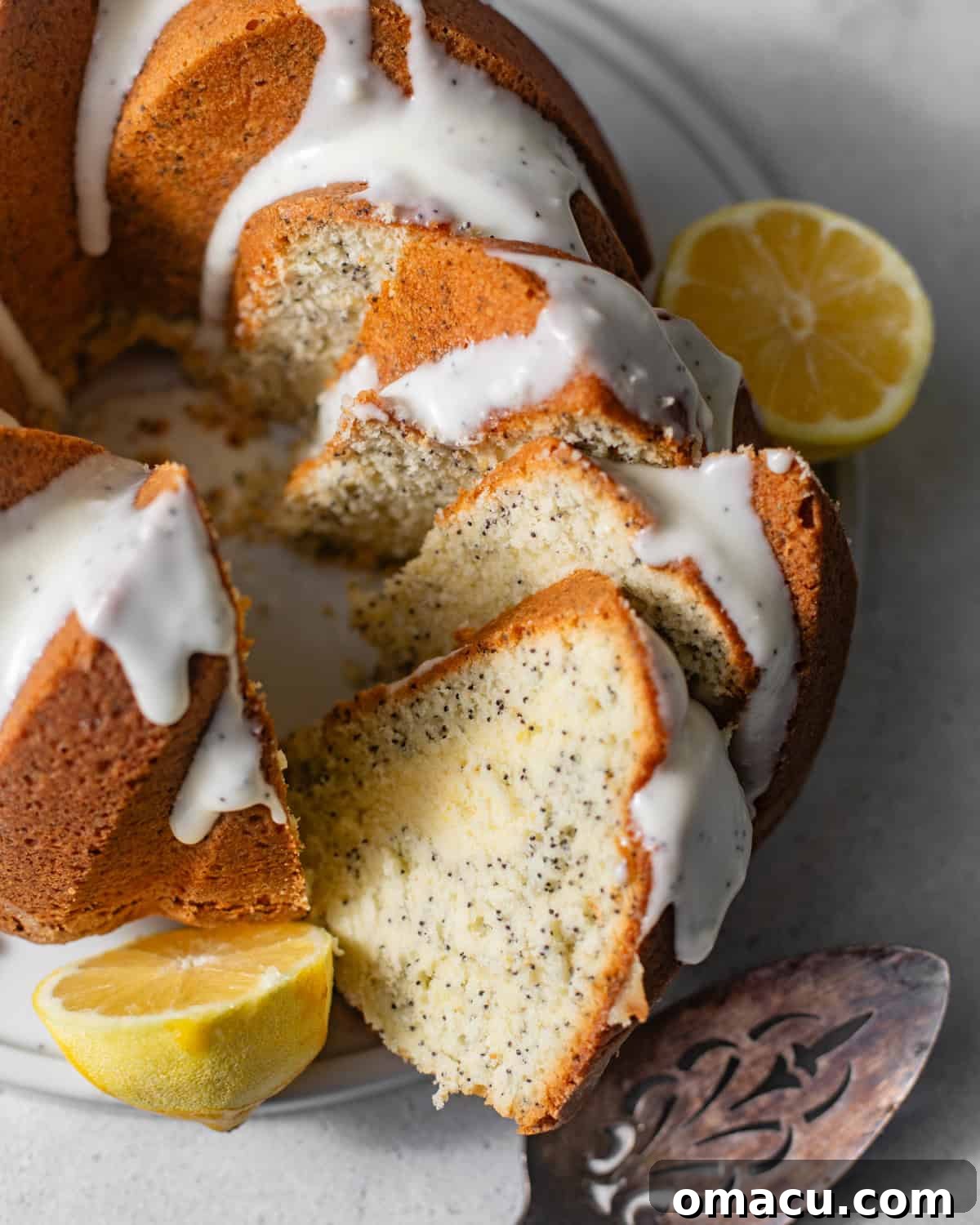 A perfect slice of moist lemon poppy seed cake, showing its delicate crumb and poppy seeds, served on a white plate, ready to be enjoyed.