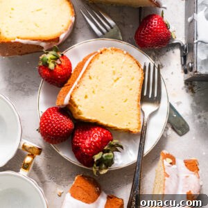 A slice of whipping cream pound cake on a plate with strawberries and forks.