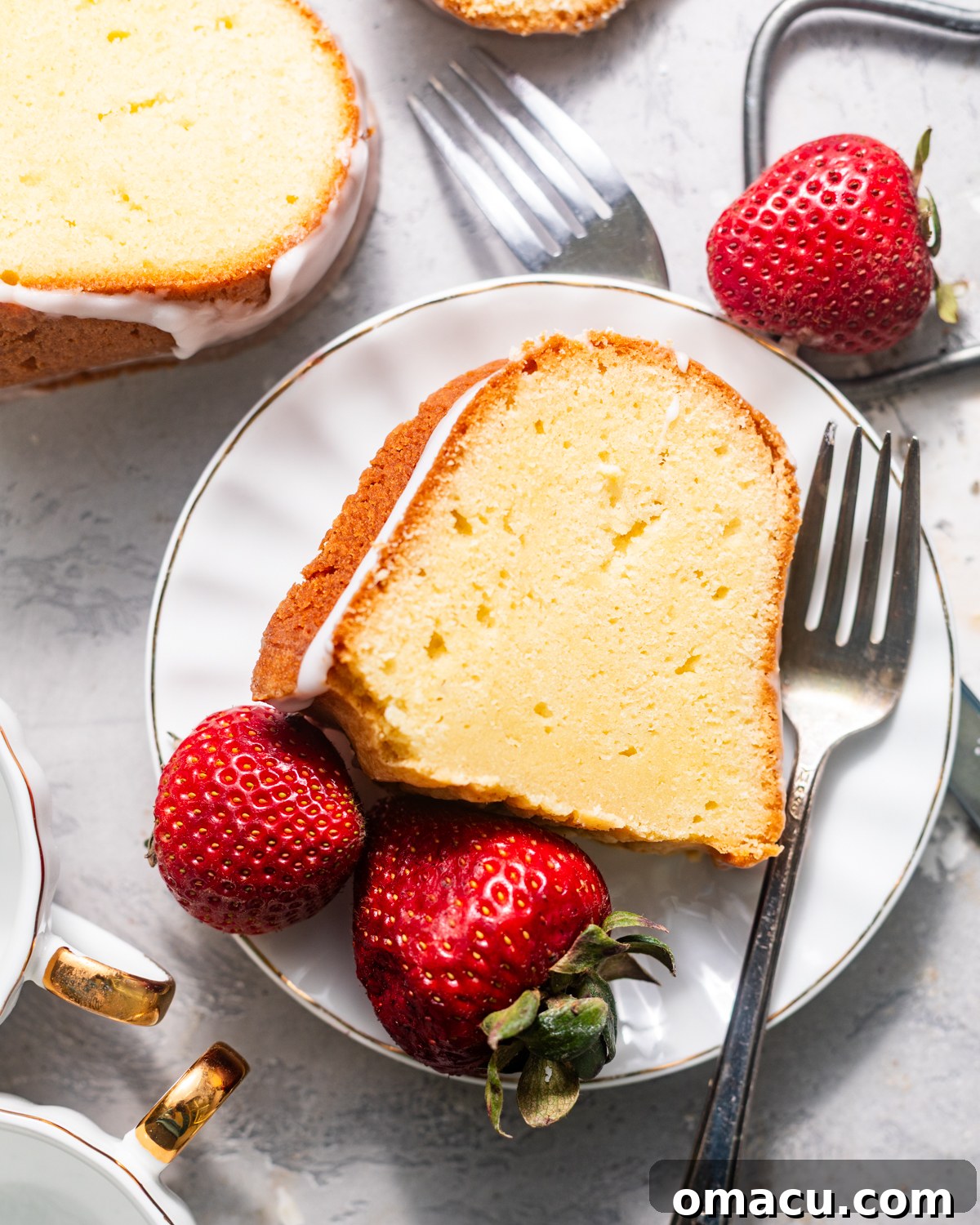 A close-up view of a perfectly baked whipping cream pound cake slice on a pristine white plate, showcasing its golden crust and moist, dense crumb.