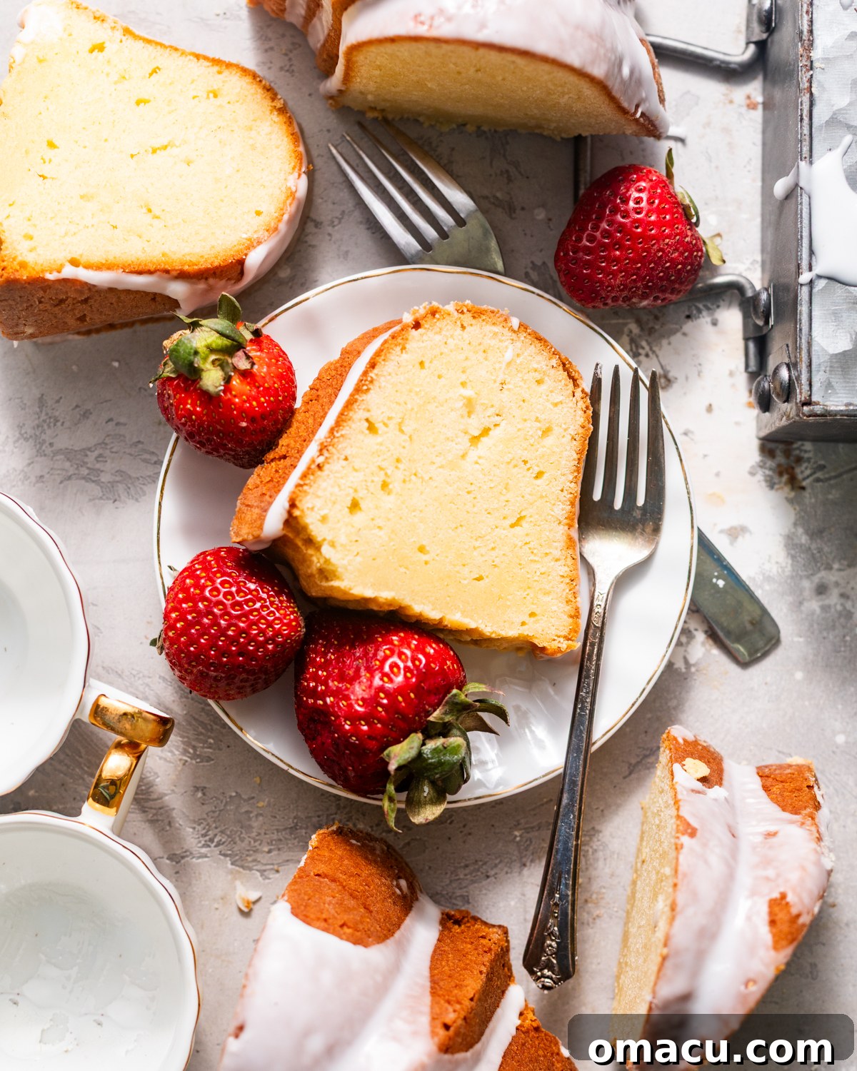 A beautiful slice of whipping cream pound cake, elegantly plated with fresh strawberries and forks, ready to be served.