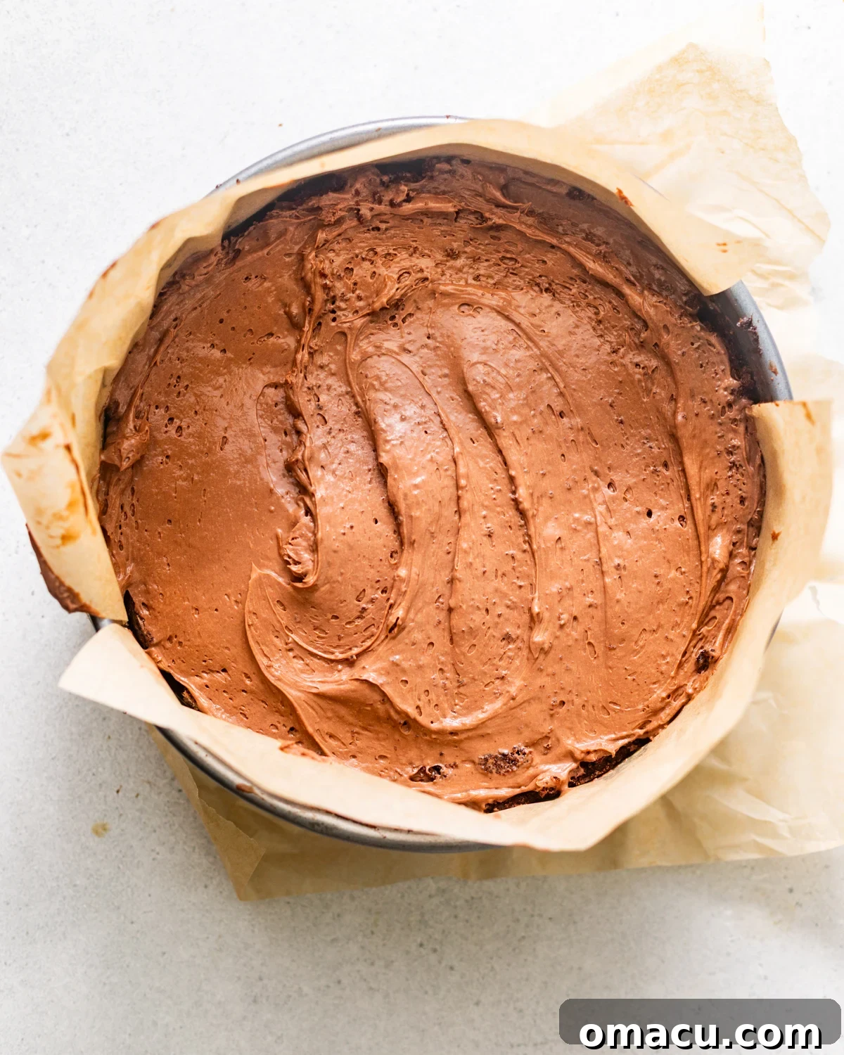 Half of the fluffy chocolate mousse is spread generously over the ganache-covered chocolate cake layer, creating a thick, creamy filling.
