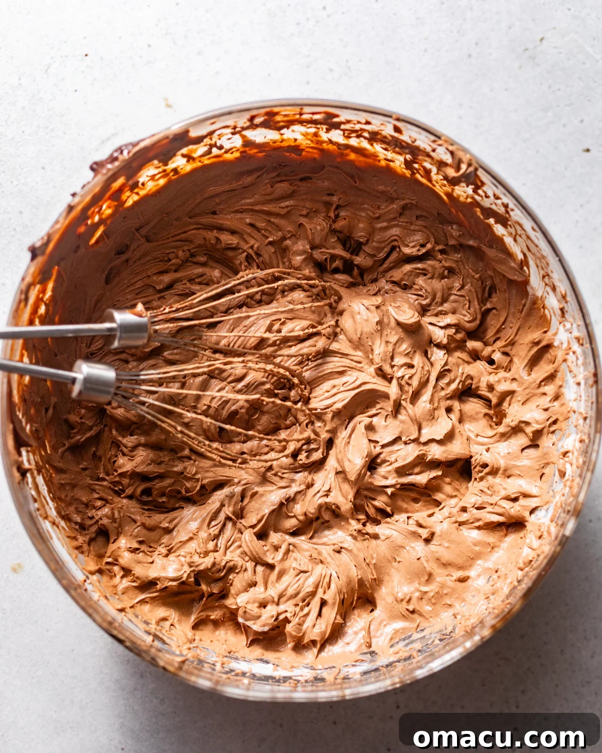 The chocolate base and whipped cream are folded together in a bowl, creating a light, airy, and rich chocolate mousse.