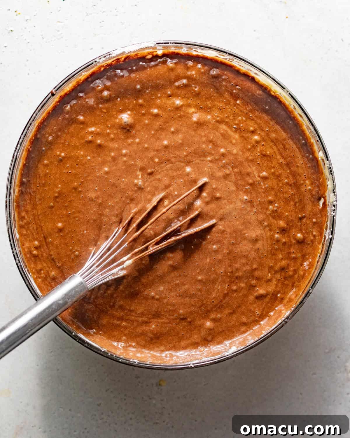 The complete chocolate cake batter, smooth and rich, is whisked together in a mixing bowl, ready for baking.