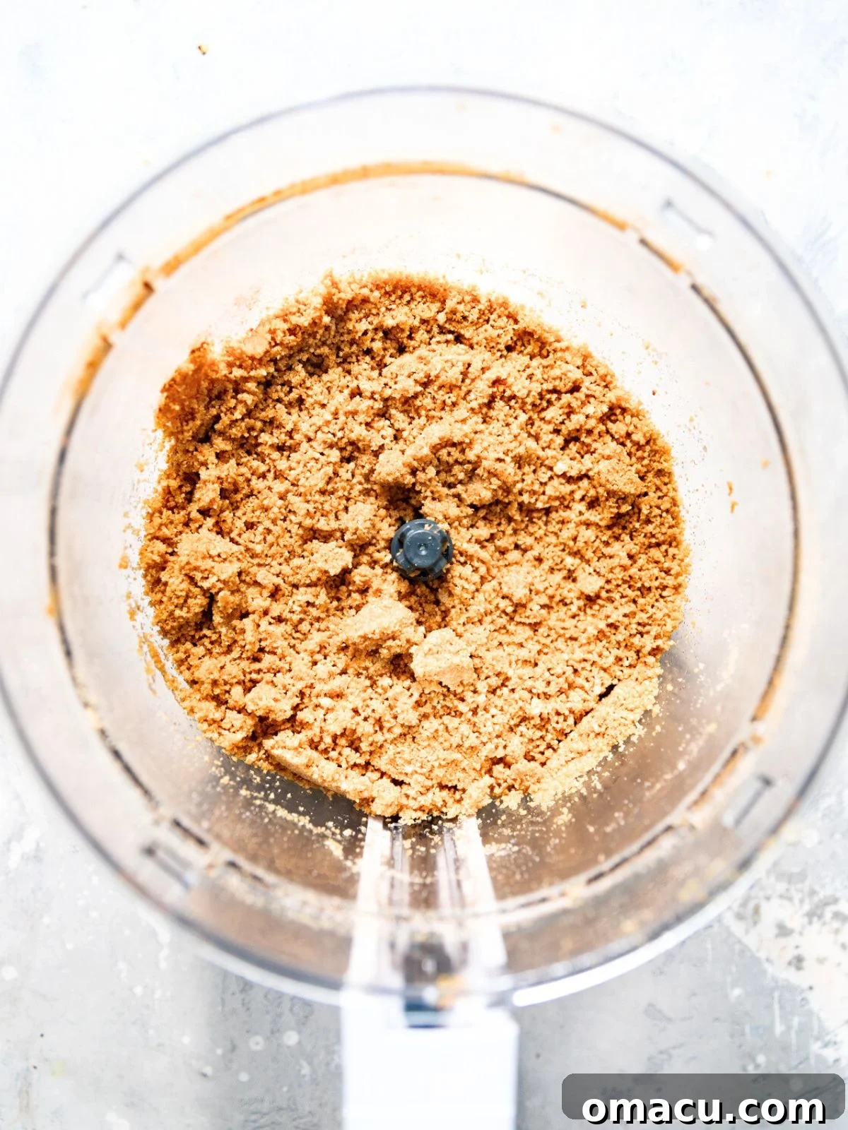 Biscoff cookies being crushed into fine crumbs in a food processor.