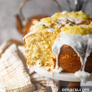 sliced pineapple pound cake on a cake stand covered in a pineapple glaze and topped with crushed pineapples.