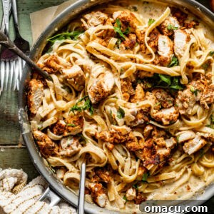 blackened chicken alfredo in a skillet topped with parsley.