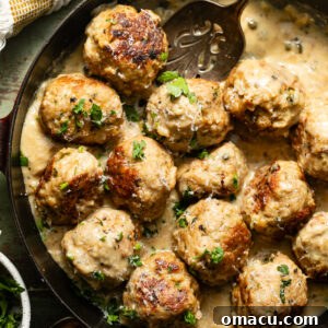 chicken piccata meatballs in a skillet topped with parsley and sliced lemons.