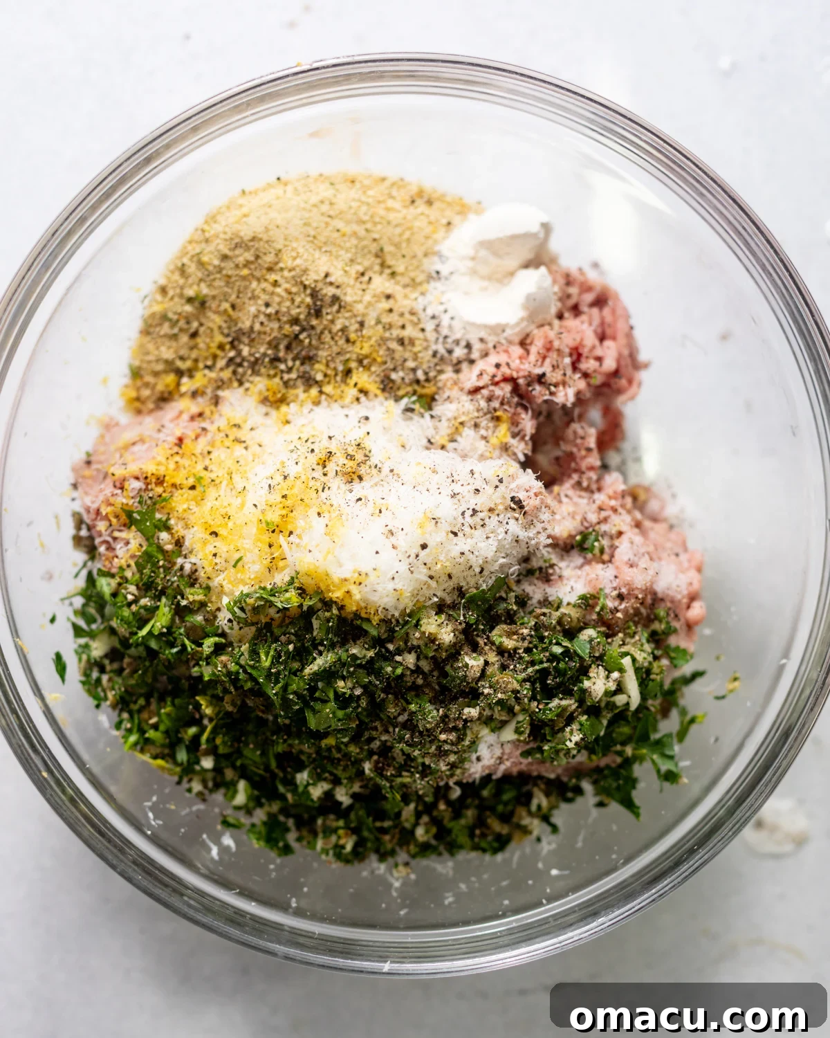 ground chicken, lemon zest, parmesan, parsley, breadcrumbs, eggs, and seasonings in a bowl. 