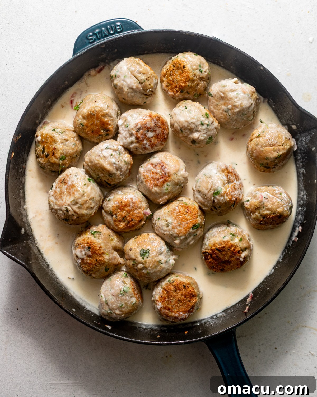 meatballs being cooked in a creamy lemon piccata sauce.