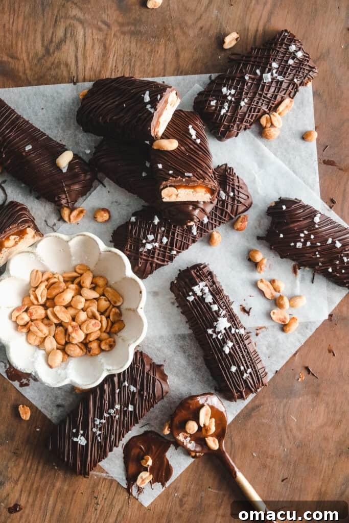 Delicious homemade Snickers bars, perfectly layered with nougat, peanuts, caramel, and chocolate, ready to be enjoyed.
