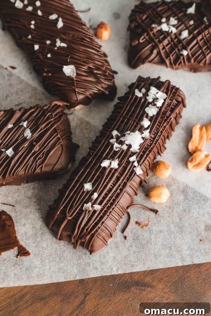 A close-up of a homemade Snickers bar, showcasing the distinct layers of chocolate, caramel, peanuts, and nougat.