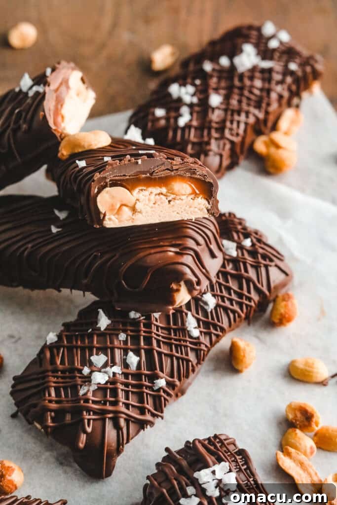 Homemade Snickers bars stacked, showing their thick, delectable layers.