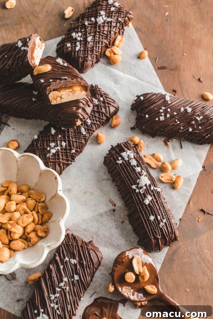 The nougat layer being smoothed into an 8x8 pan lined with parchment paper, topped with a generous sprinkle of peanuts.