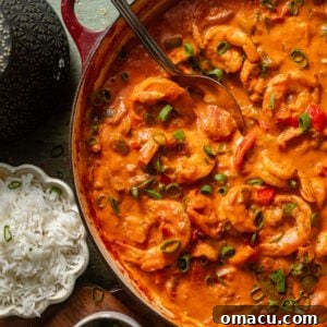 shrimp creole in a large pot with a serving spoon next to a bowl of rice.