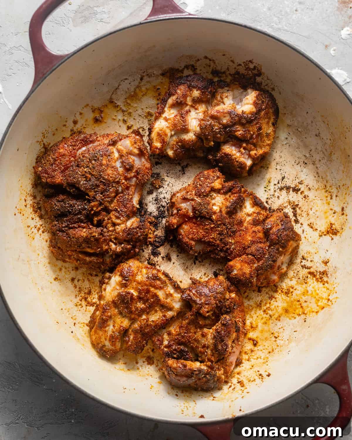 Perfectly seared chicken thighs displaying a golden-brown crust in a large skillet, ready to be removed.