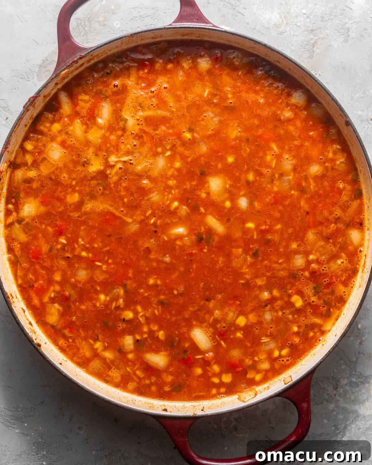 Rice, black beans, salsa, beer, and chicken broth simmering together in a large skillet, absorbing rich flavors.