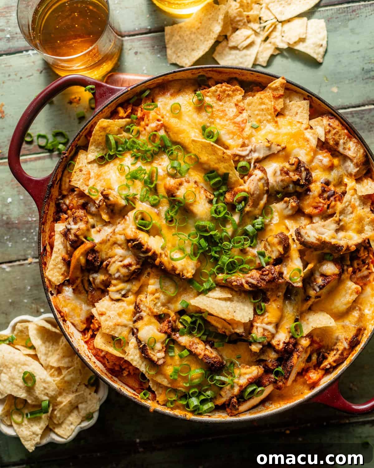 The finished cheesy Mexican chicken and rice in a large skillet, topped with crunchy tortilla chips, melted cheese, and fresh garnishes, ready to serve.