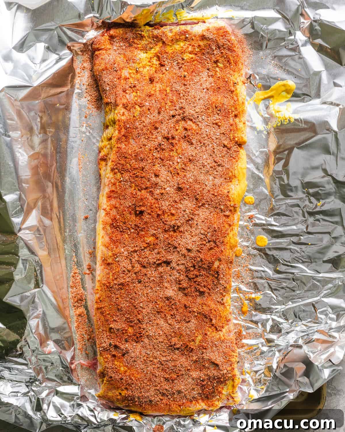Seasoned ribs generously coated with dry rub on a baking sheet.
